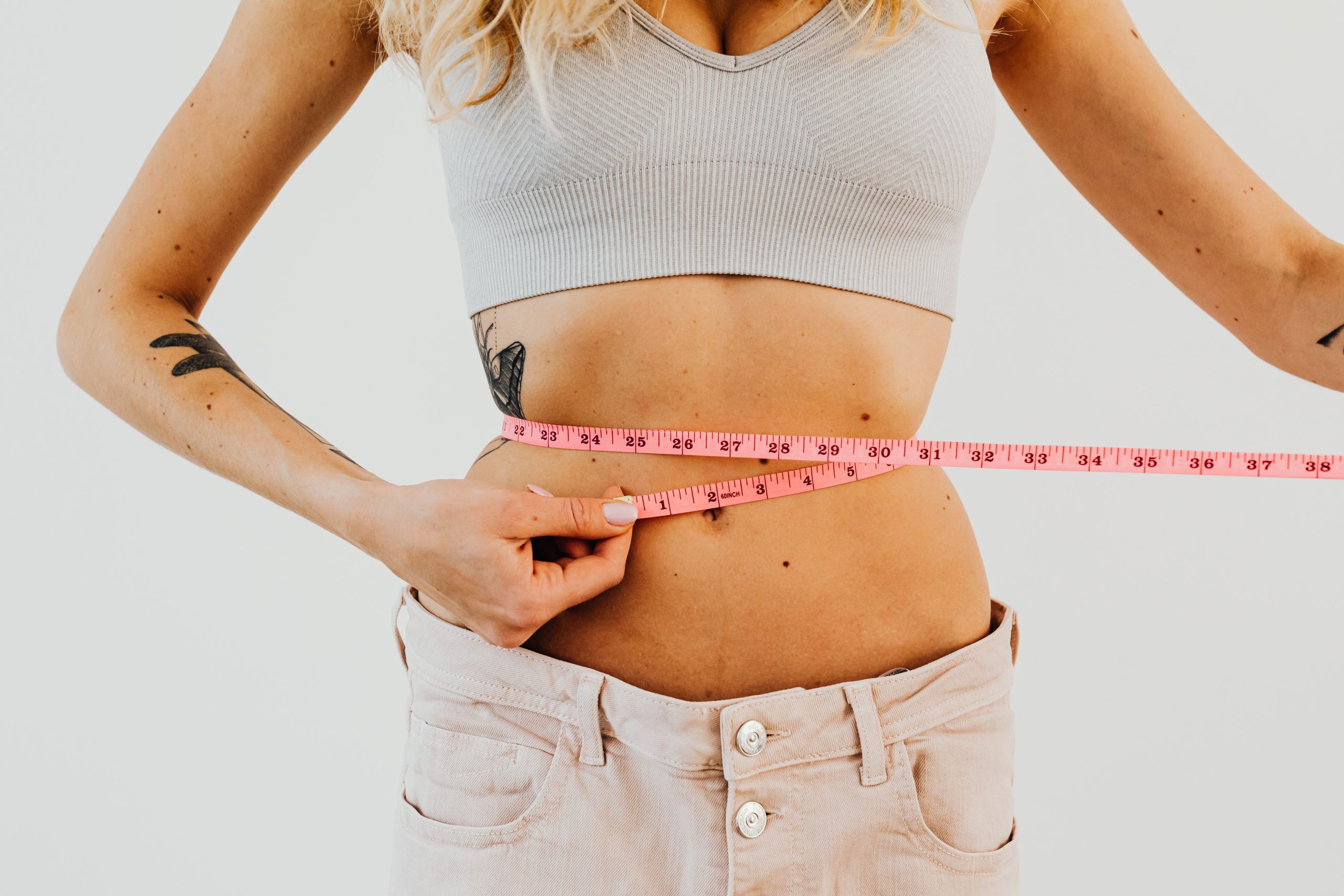 Woman measuring waist with tape measure for weight loss progress